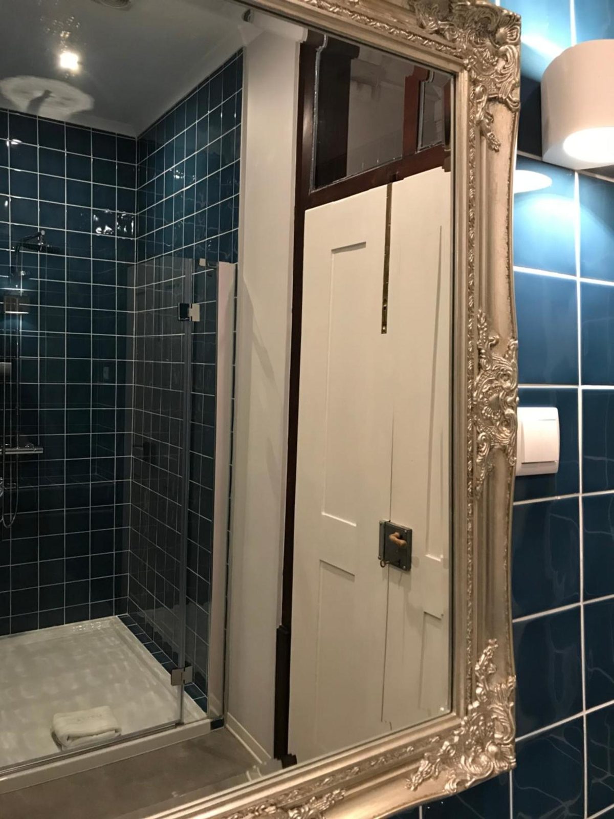 O chuveiro da casa de banho azul, visto ao espelho