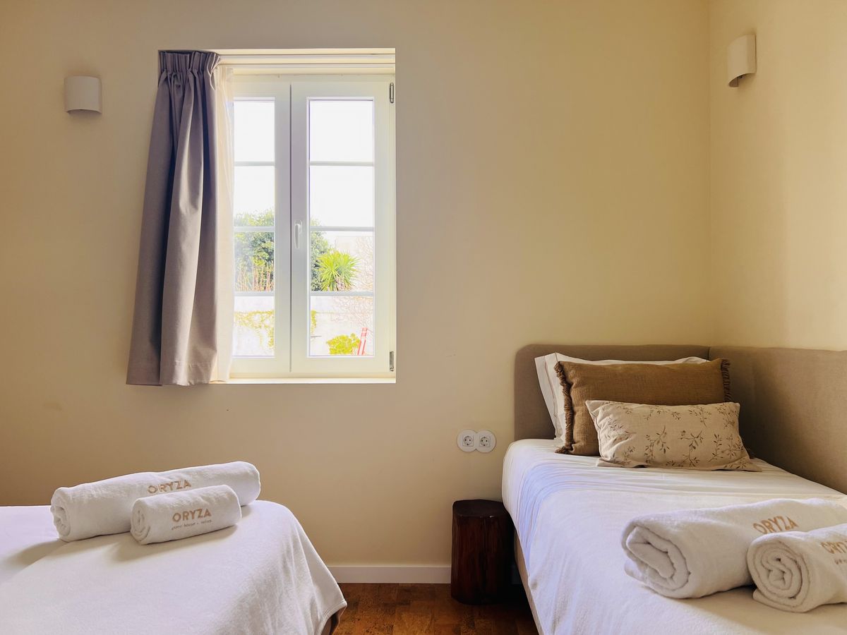 A janela do quarto, com cortinas azuis, ao lado da cama