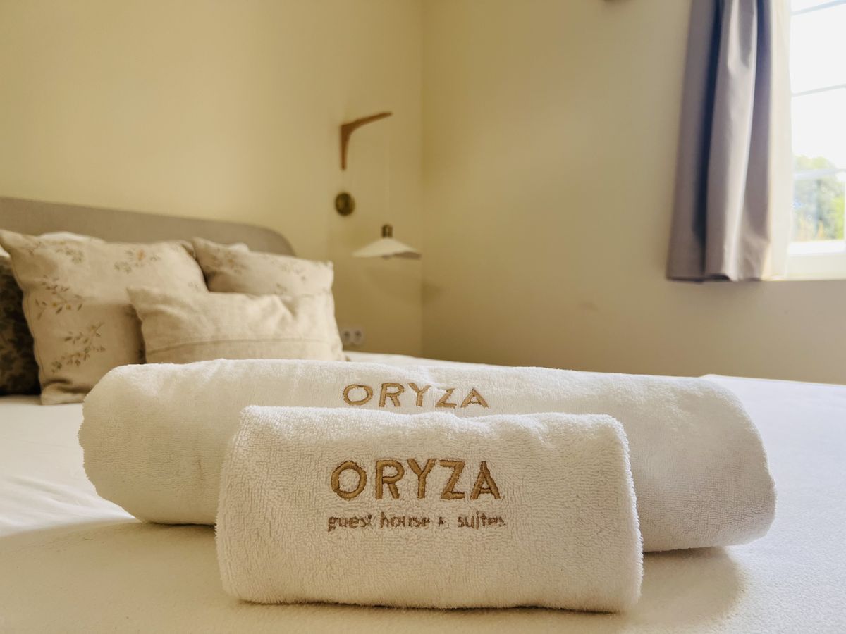 Toalhas bordadas com o nome Oryza sobre a cama