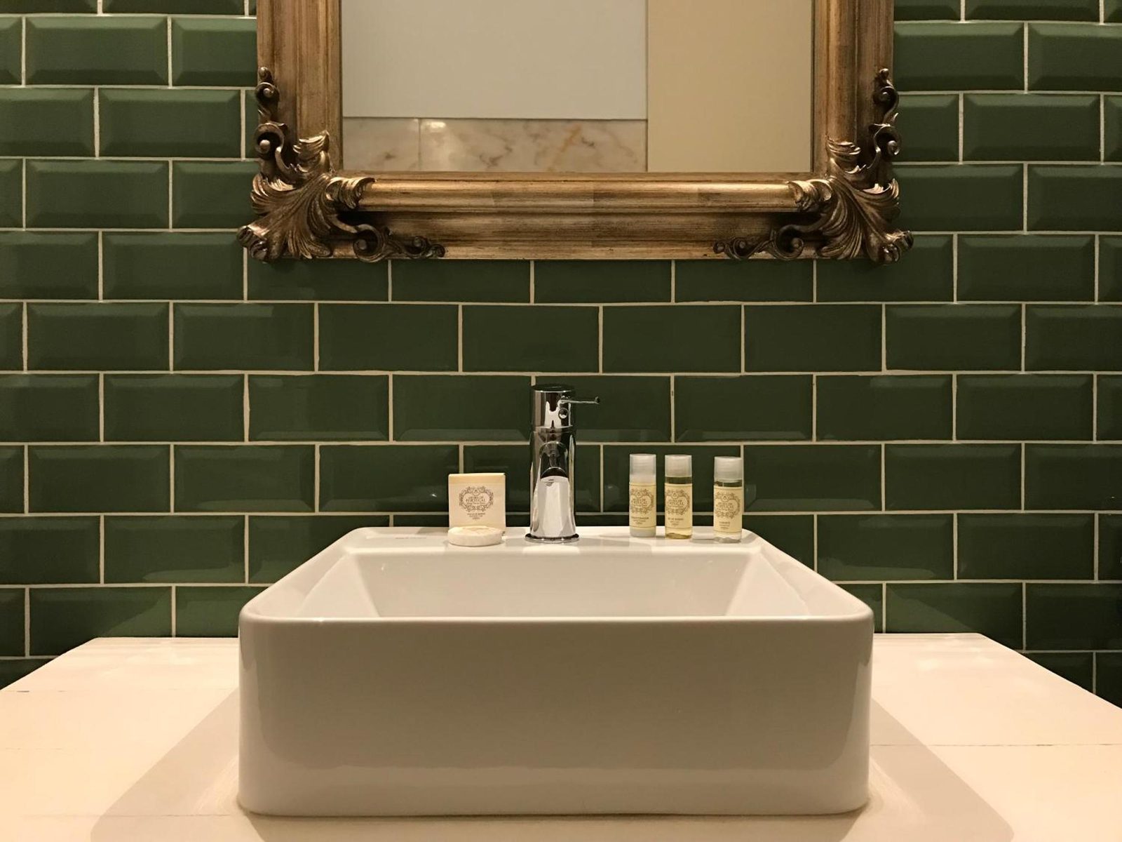 Lavatório sobre o azulejo verde da casa de banho