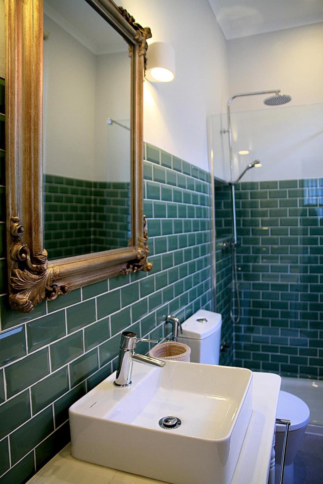 Casa de banho de azulejo verde, com espelho dourado