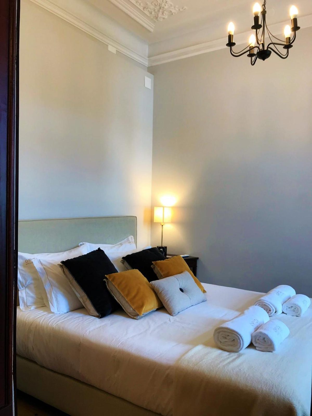 A cama sob o lustre, com a janela ao lado