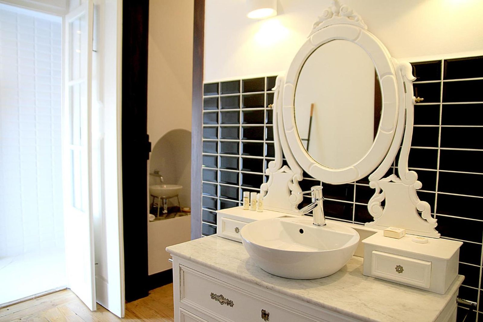 A casa de banho, com o toucador branco e azulejo preto